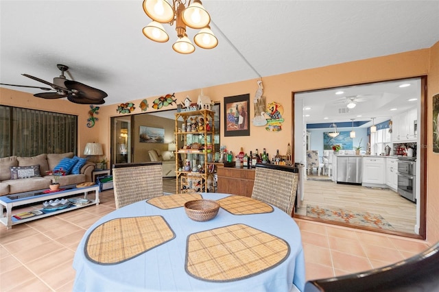 dining space featuring light tile patterned flooring and ceiling fan with notable chandelier