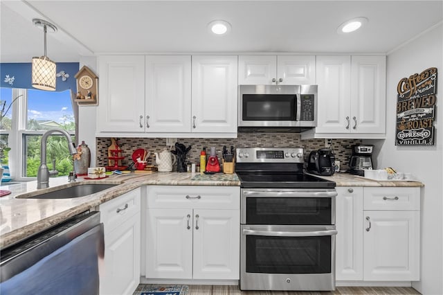 kitchen with decorative backsplash, white cabinetry, stainless steel appliances, and a sink