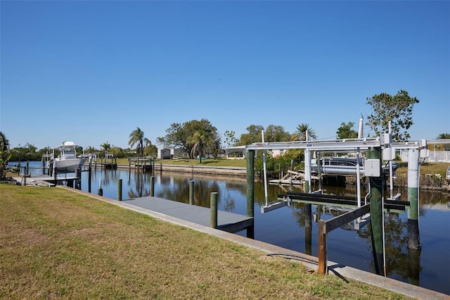 dock area with a water view, boat lift, and a lawn