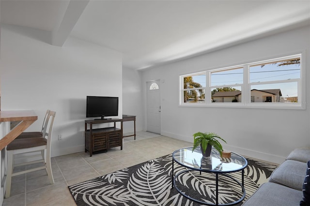 living area with beamed ceiling, light tile patterned floors, and baseboards