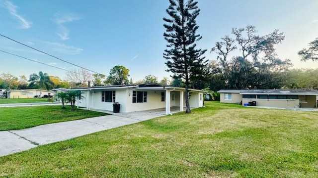 ranch-style home featuring an attached carport, a front yard, driveway, and stucco siding