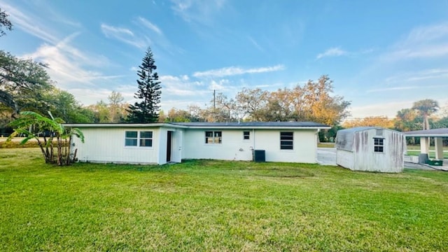 back of house with an outbuilding, cooling unit, a storage unit, and a yard