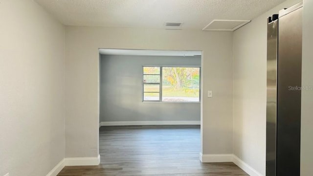 unfurnished room featuring dark wood-style floors, baseboards, and a textured ceiling