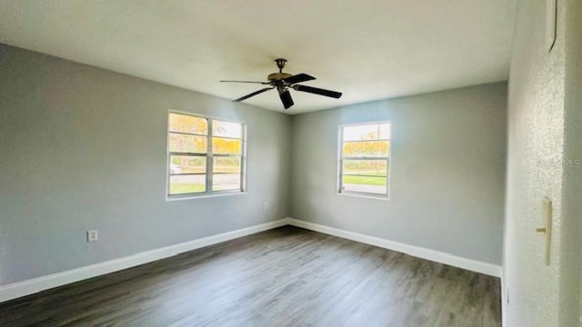 empty room with a ceiling fan, dark wood-type flooring, and baseboards