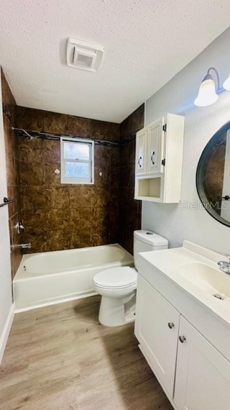 full bath featuring a textured ceiling, wood finished floors, washtub / shower combination, and toilet