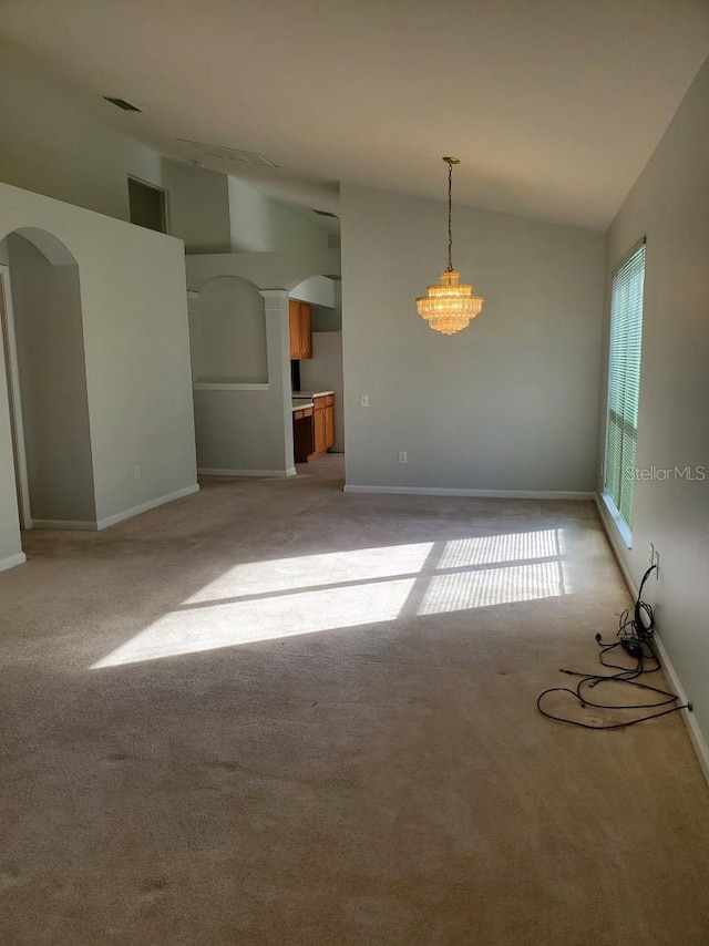 empty room featuring baseboards, light colored carpet, arched walkways, and high vaulted ceiling