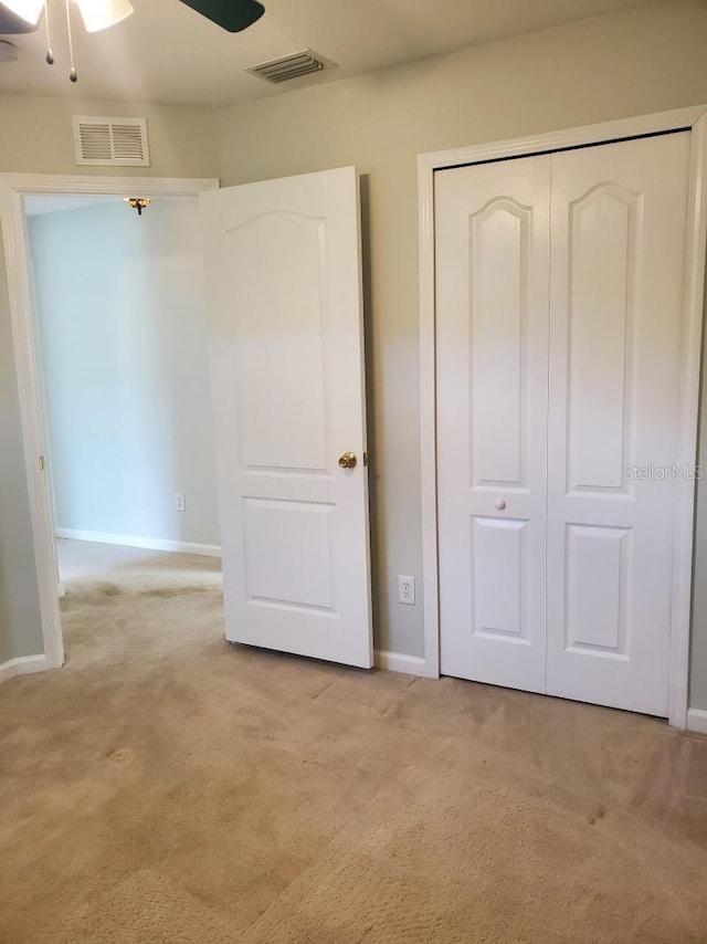 unfurnished bedroom featuring a closet, visible vents, light colored carpet, and baseboards