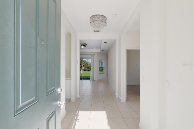 corridor featuring a notable chandelier and light tile patterned flooring