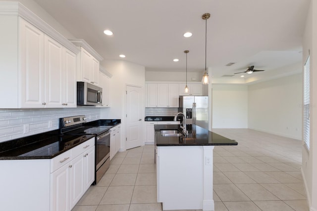 kitchen with a sink, ceiling fan, light tile patterned floors, stainless steel appliances, and a kitchen island with sink