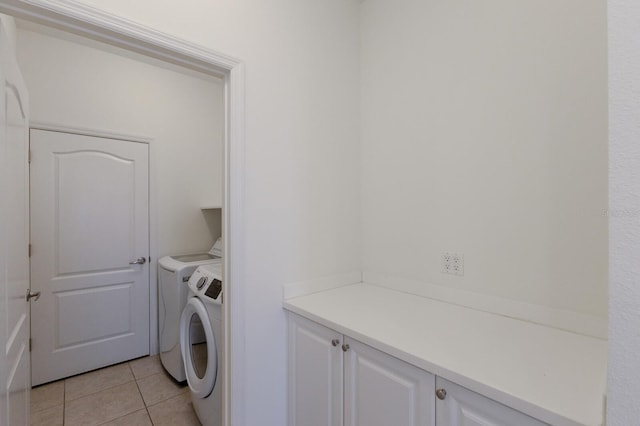 washroom with light tile patterned floors, cabinet space, and separate washer and dryer