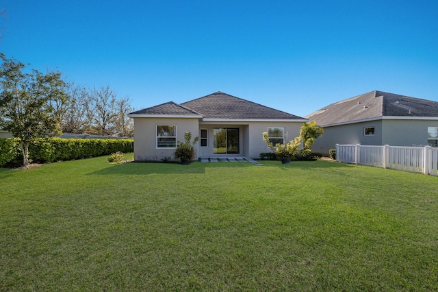 back of house with fence, a lawn, and stucco siding