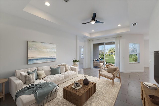 living area featuring tile patterned floors, visible vents, recessed lighting, and a tray ceiling