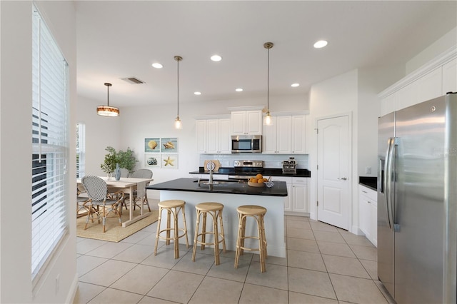 kitchen featuring backsplash, dark countertops, stainless steel appliances, white cabinets, and light tile patterned floors