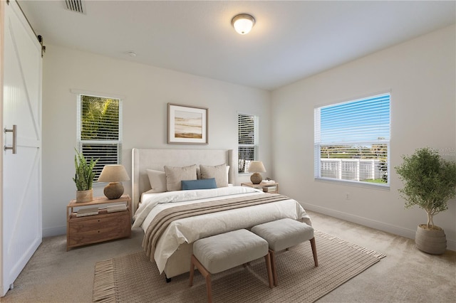 bedroom with visible vents, light colored carpet, baseboards, and a barn door