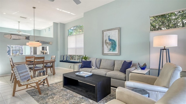 living area featuring light tile patterned floors, visible vents, baseboards, and ceiling fan