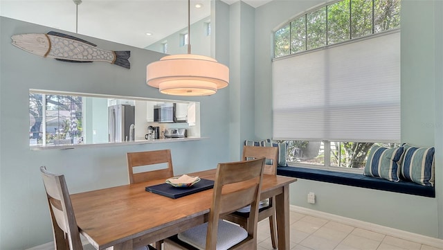 dining room featuring light tile patterned floors, a healthy amount of sunlight, and a towering ceiling