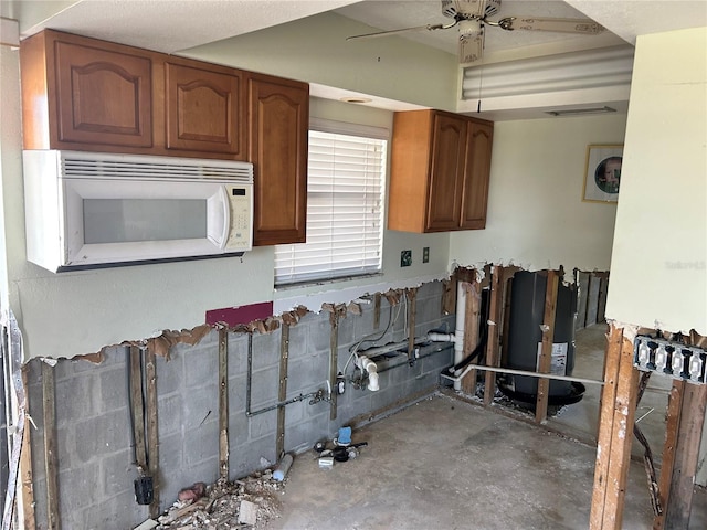 kitchen with a ceiling fan, unfinished concrete floors, white microwave, and brown cabinets