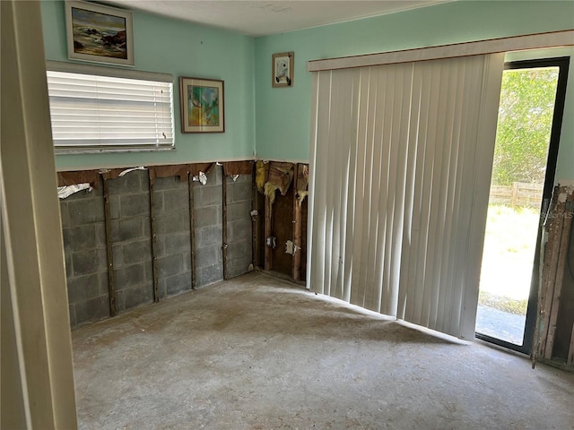 interior space with plenty of natural light, concrete block wall, and concrete flooring