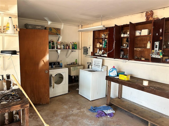 interior space with a sink, concrete block wall, separate washer and dryer, and laundry area