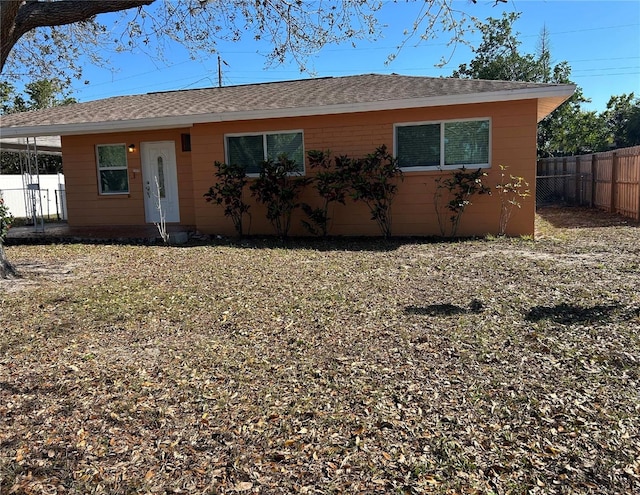 view of front facade with roof with shingles and fence