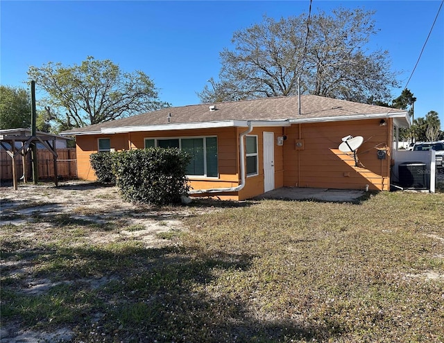 rear view of property with a lawn, cooling unit, and fence