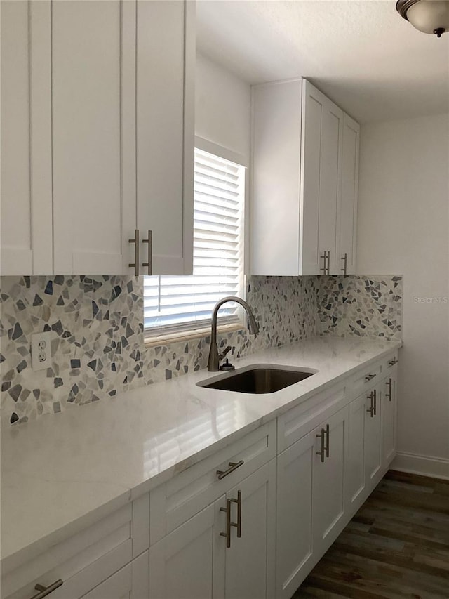 kitchen with dark wood-style floors, baseboards, a sink, white cabinets, and tasteful backsplash