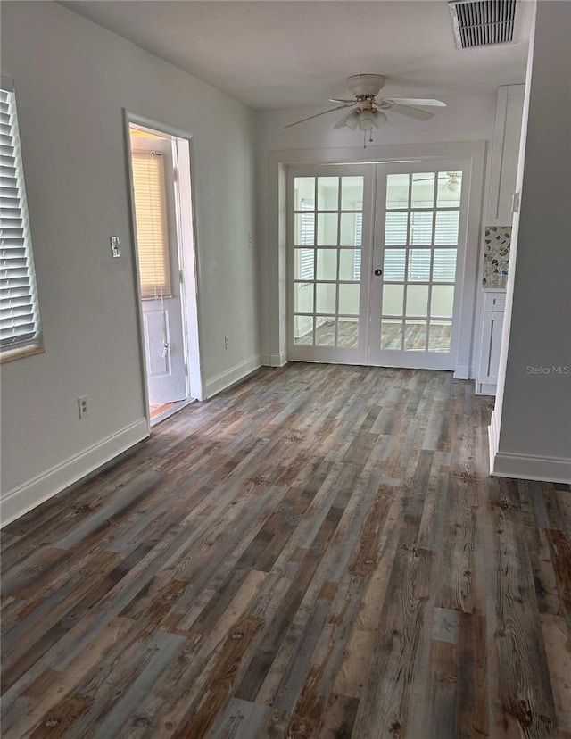 unfurnished living room featuring dark wood-style floors, visible vents, baseboards, and ceiling fan