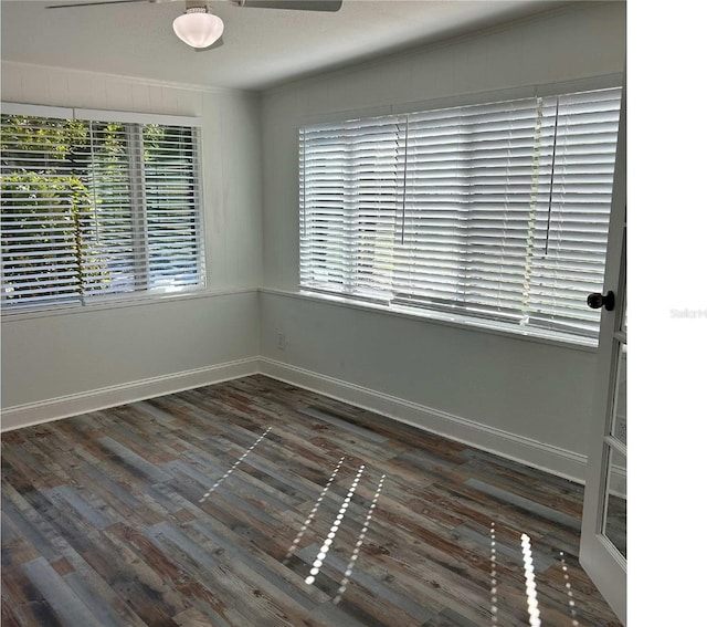 spare room with baseboards, dark wood-type flooring, ceiling fan, and ornamental molding