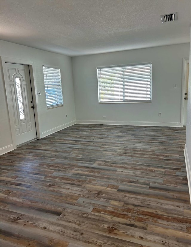 entryway featuring visible vents, plenty of natural light, a textured ceiling, and dark wood-style flooring