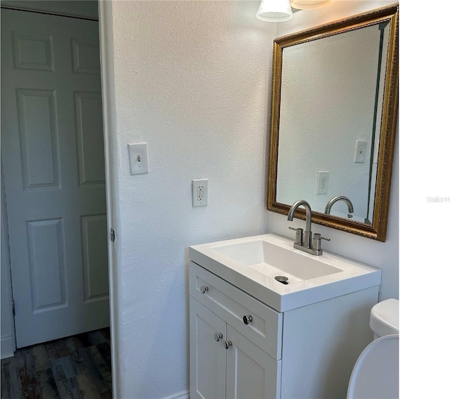 bathroom with toilet, wood finished floors, and vanity