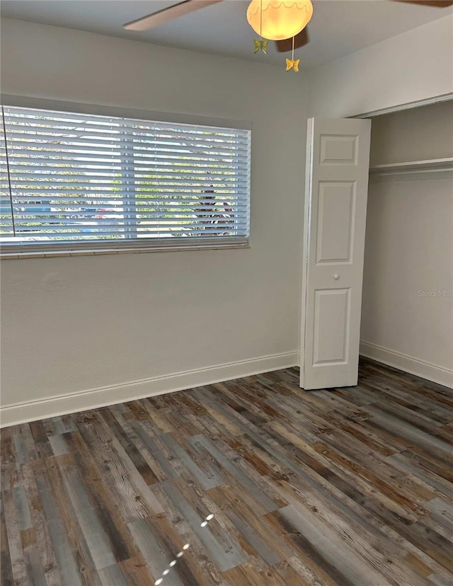 unfurnished bedroom featuring a ceiling fan, baseboards, dark wood-style flooring, and a closet