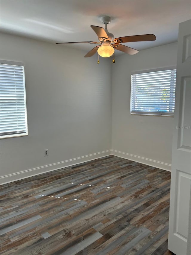 spare room with dark wood finished floors, a ceiling fan, and baseboards