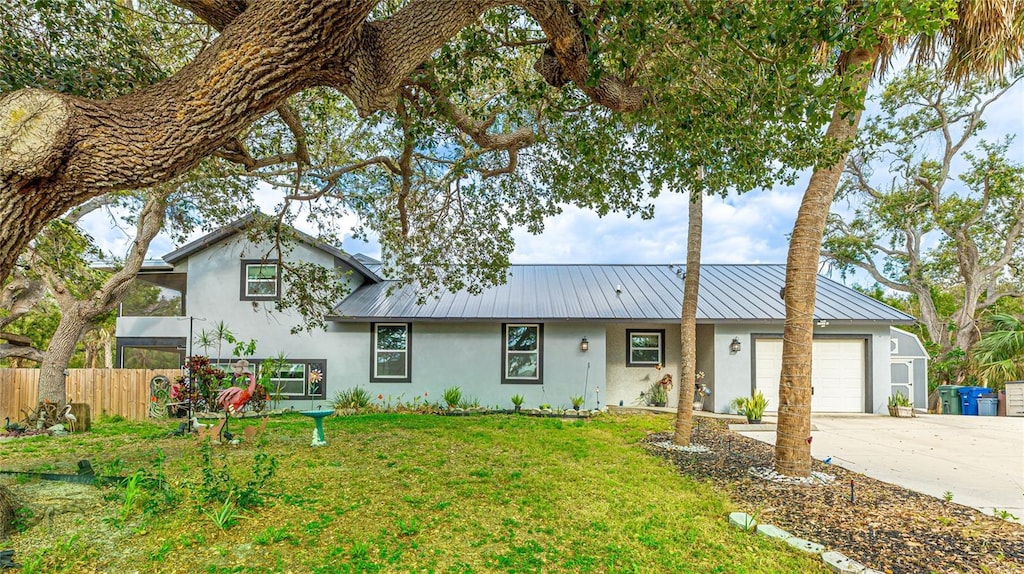 5671 Osprey Rd, Venice, FL 34293 - split level home featuring stucco siding, concrete driveway, a front lawn, a garage, and metal roof