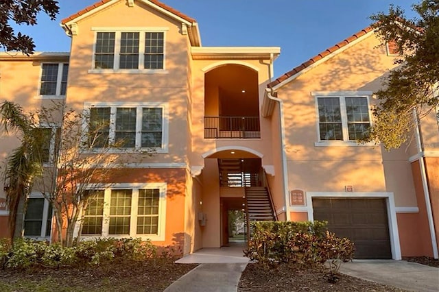 view of front of home featuring stairs, concrete driveway, a garage, and stucco siding