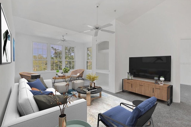 living area featuring baseboards, light colored carpet, lofted ceiling, and a ceiling fan