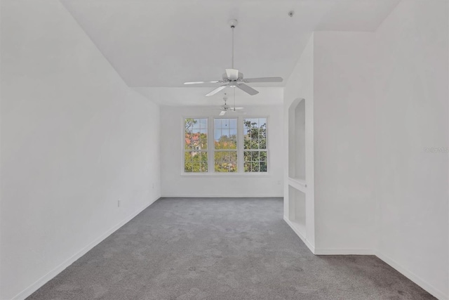 carpeted spare room with arched walkways, baseboards, and ceiling fan