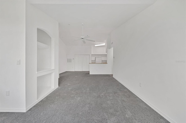 carpeted spare room featuring baseboards, arched walkways, and ceiling fan