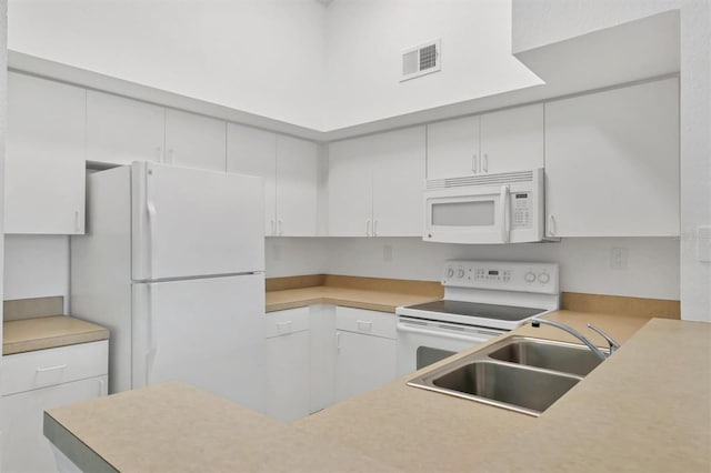 kitchen with white appliances, visible vents, a sink, light countertops, and white cabinets