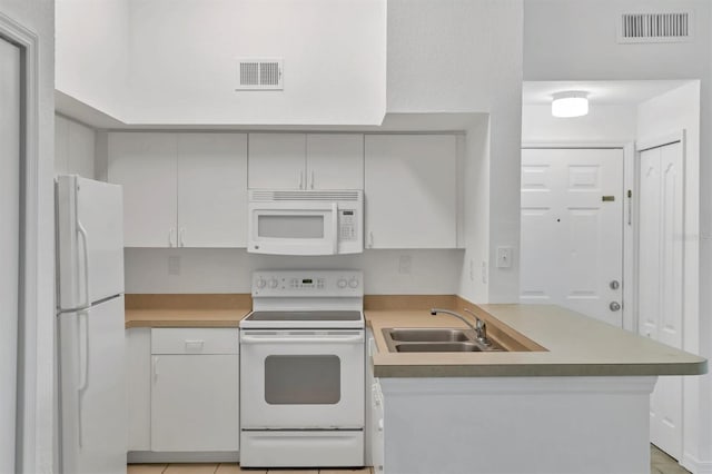 kitchen featuring white appliances, a peninsula, visible vents, and a sink