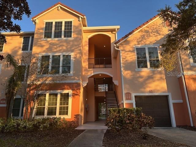 view of front of home featuring stairs, stucco siding, driveway, a balcony, and an attached garage