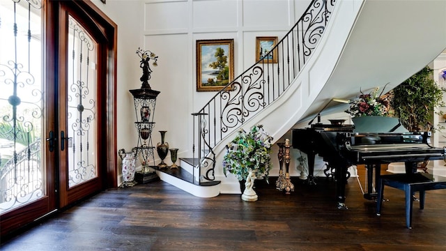 foyer entrance with dark wood-style floors, stairs, and a decorative wall