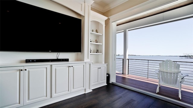 unfurnished living room with dark wood-type flooring, built in features, a water view, and ornamental molding