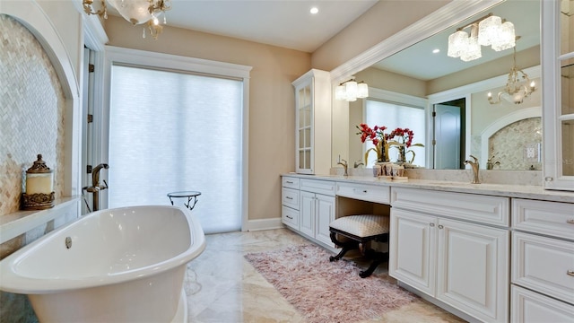 bathroom with vanity, baseboards, an inviting chandelier, a soaking tub, and marble finish floor