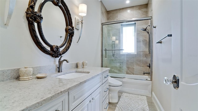 bathroom featuring enclosed tub / shower combo, toilet, vanity, and baseboards