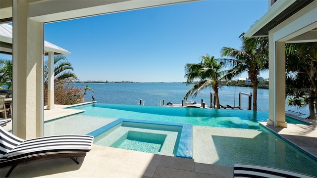 view of pool with a patio area, a water view, and a pool with connected hot tub