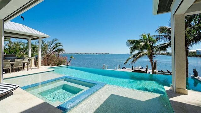 view of swimming pool with a water view, a pool with connected hot tub, and a patio area