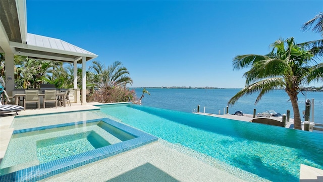 view of pool featuring a patio, a pool with connected hot tub, outdoor dry bar, and a water view