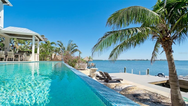 view of swimming pool featuring a patio area, an infinity pool, and a water view