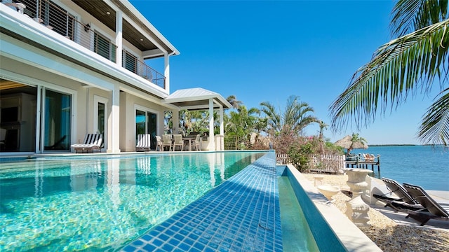 view of pool with outdoor dining space, a patio, and a water view