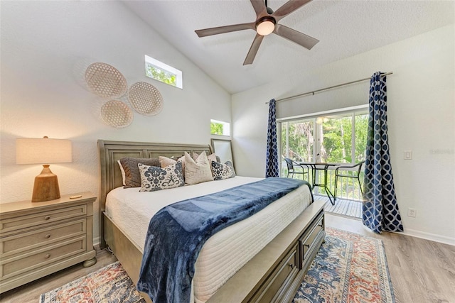 bedroom with vaulted ceiling, multiple windows, light wood-style floors, and access to outside